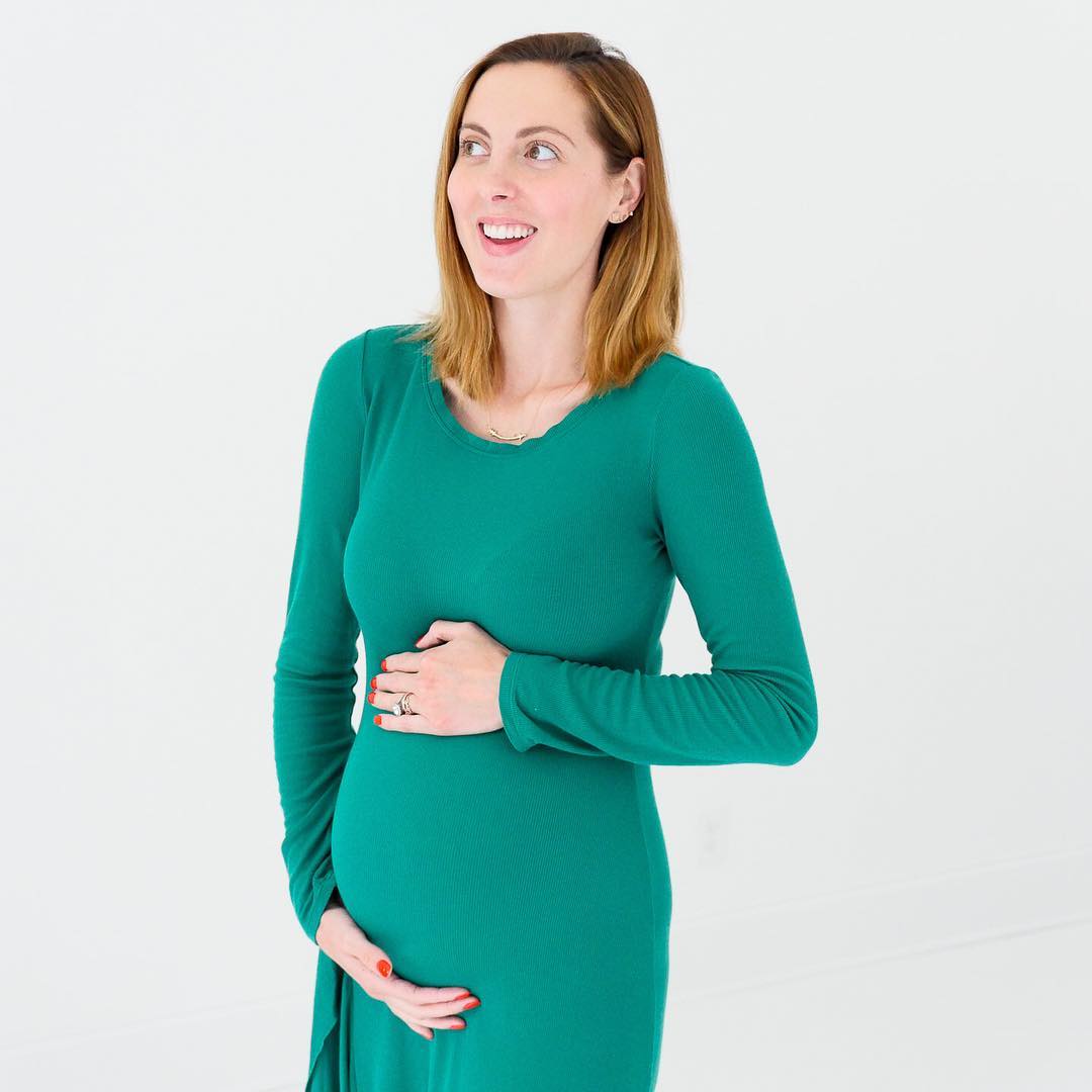 Eva Amurri Martino of the REZTT blog cradling her thirty three week baby bump wearing a green long sleeved maternity maxi dress