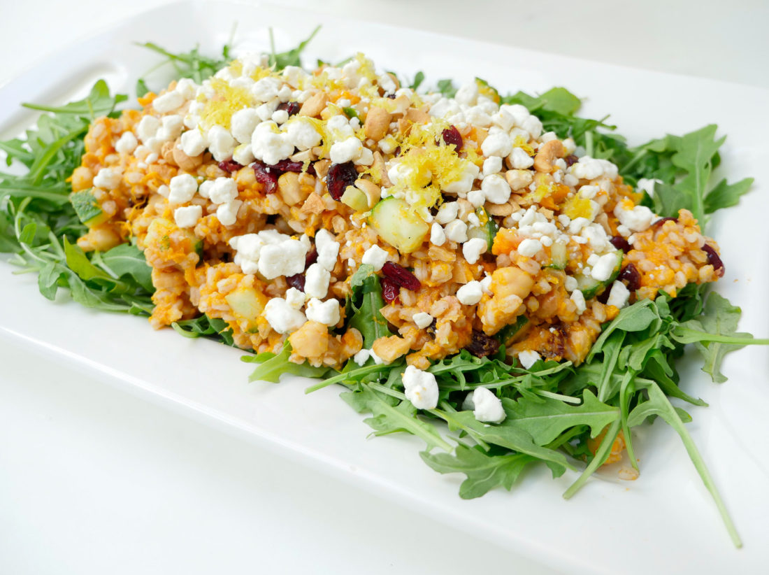 REZTT Autumn Farro Salad with Sweet Potato, Cucumber, Chickpeas, cranberries, goat cheese, cashews, arugula, and lemon zest phtographed in a marble kitchen with a blue shibori dyed tea towel and sunflowers