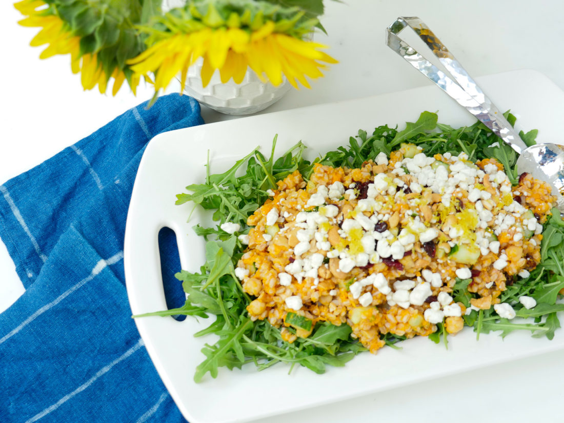 REZTT Autumn Farro Salad with Sweet Potato, Cucumber, Chickpeas, cranberries, goat cheese, cashews, arugula, and lemon zest phtographed in a marble kitchen with a blue shibori dyed tea towel and sunflowers