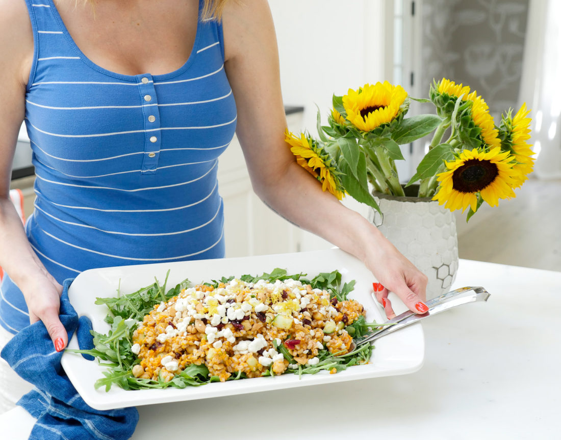REZTT Autumn Farro Salad with Sweet Potato, Cucumber, Chickpeas, cranberries, goat cheese, cashews, arugula, and lemon zest phtographed in a marble kitchen with a blue shibori dyed tea towel and sunflowers