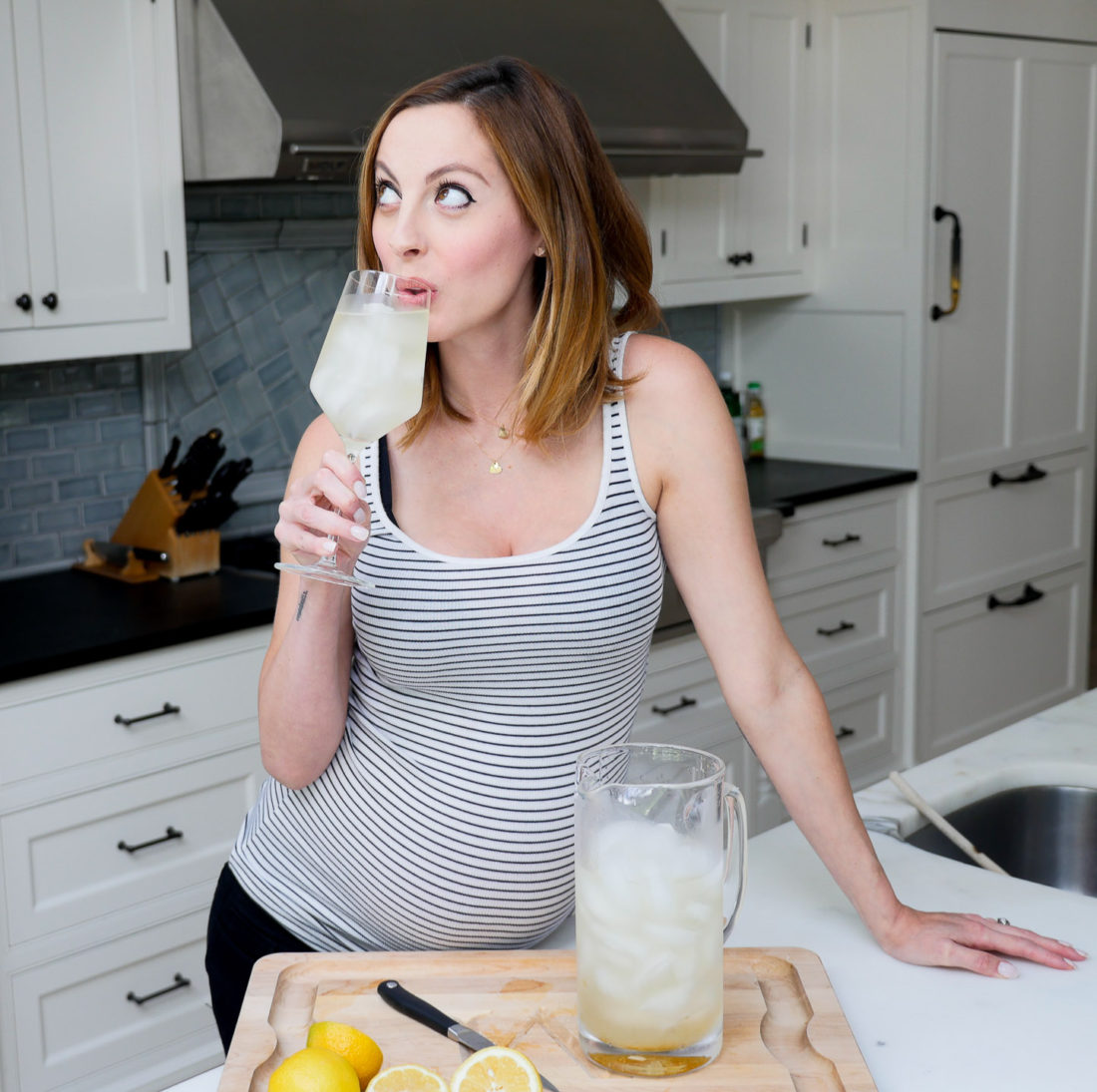 Eva Amurri Martin of lifestyle blog REZTT, drinking a home made Laborade electrolyte drink in her kitchen at 35 weeks pregnant