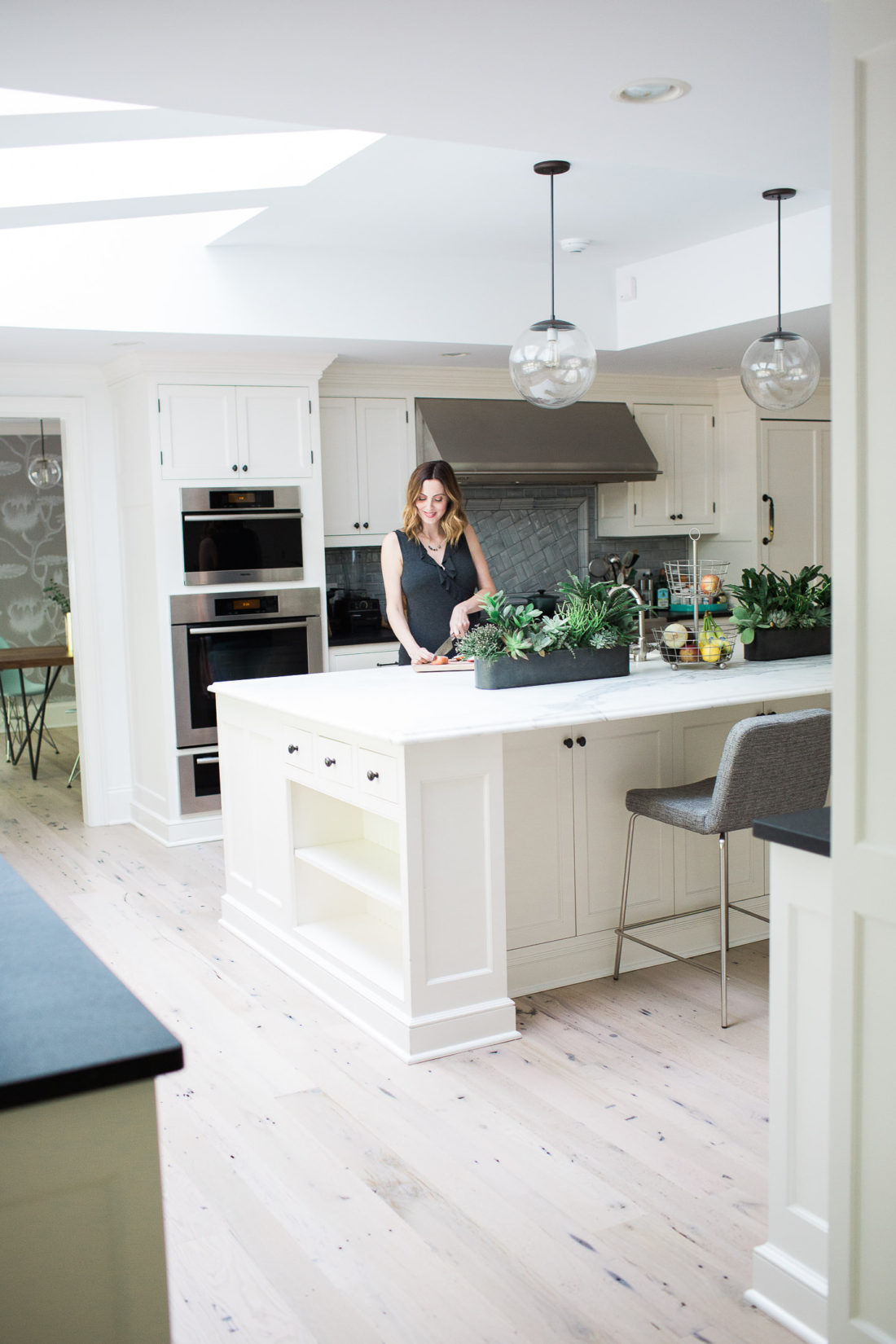 Eva Amurri Martin of lifestyle blog REZTT chopping vegetables in her white and bright kitchen in connecticut with industrial accents