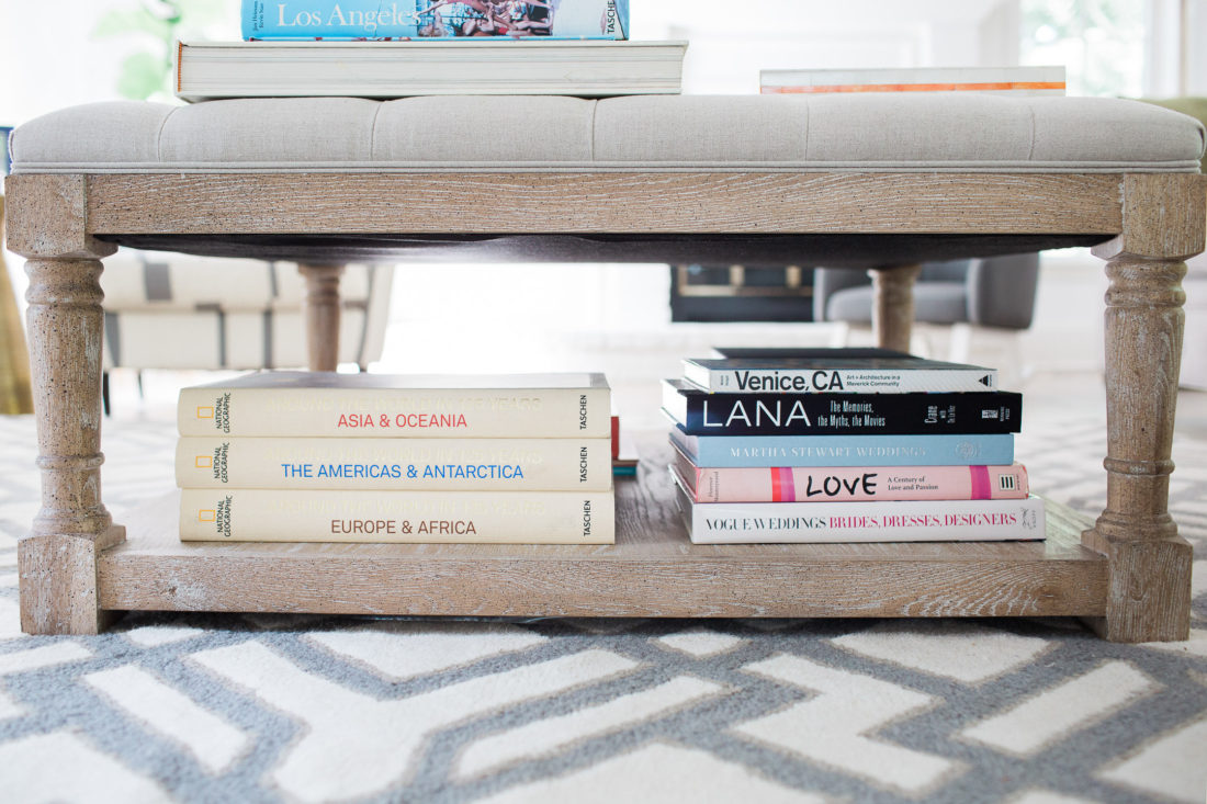 A close up of the array of coffee table books stacked under the coffee table ottoman in Eva Amurri Martino's family room of her connecticut home