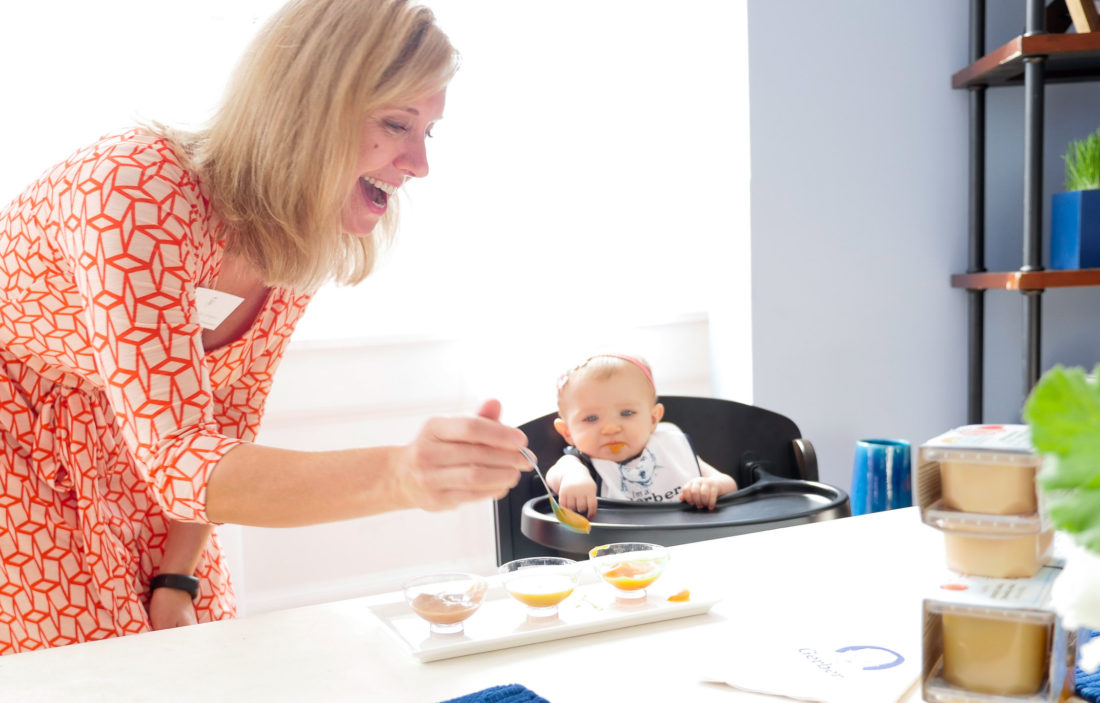 A Gerber representative feeding baby food to a child at the Gerber Babies Event in NYC, as photographed by Eva Amurri Martino of lifestyle and motherhood blog REZTT