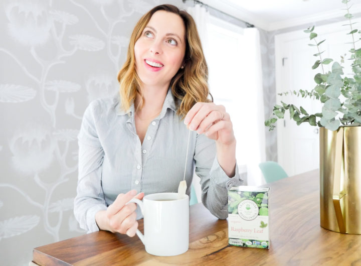 Eva Amurri Martino of lifestyle blog REZTT sits at her dining room table in connecticut wearing a blue and white striped maternity top and dunking a tea bag in to a white mug