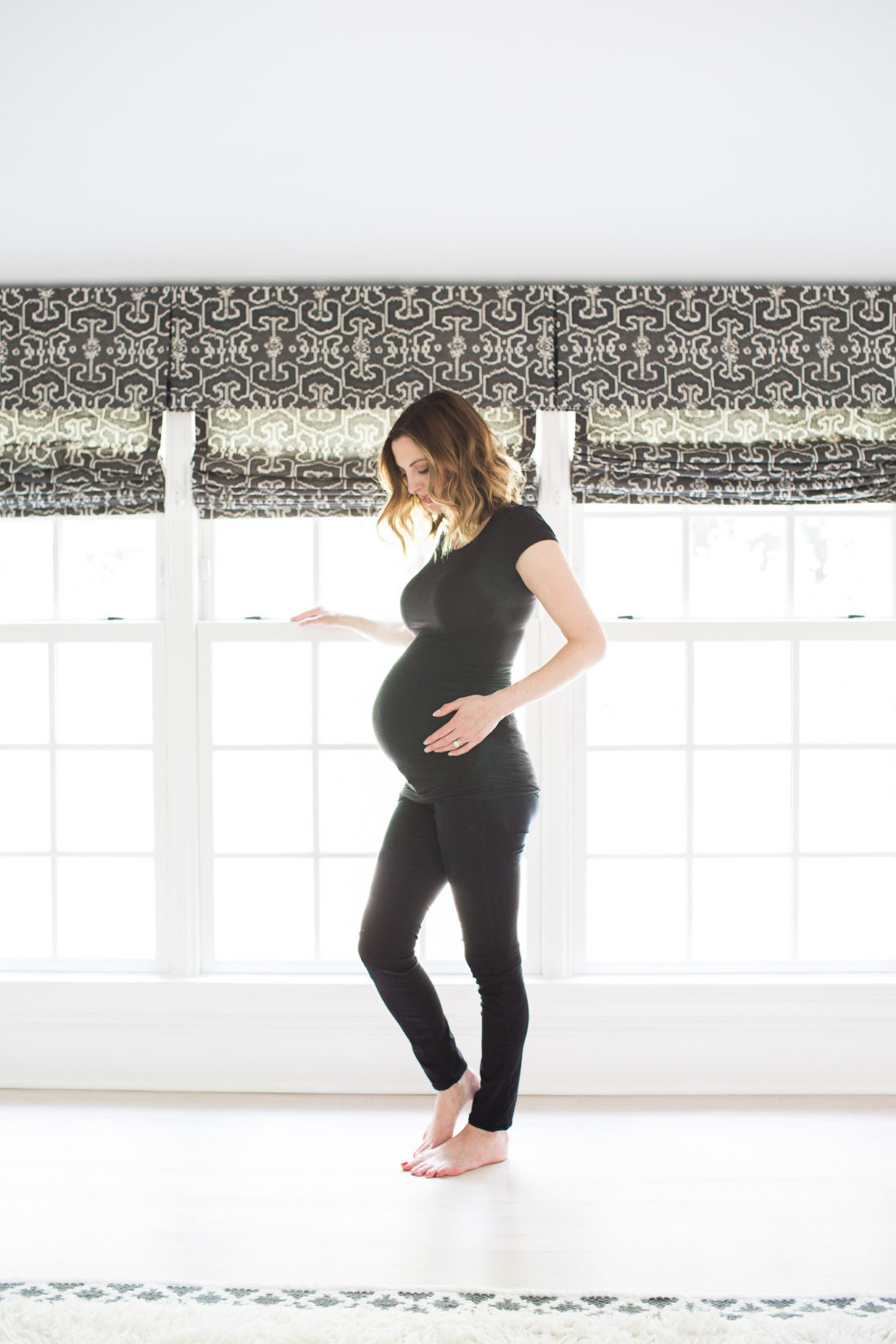Eva Amurri Martino of lifestyle and motherhood blog REZTT, wearing all black and cradling her baby bump