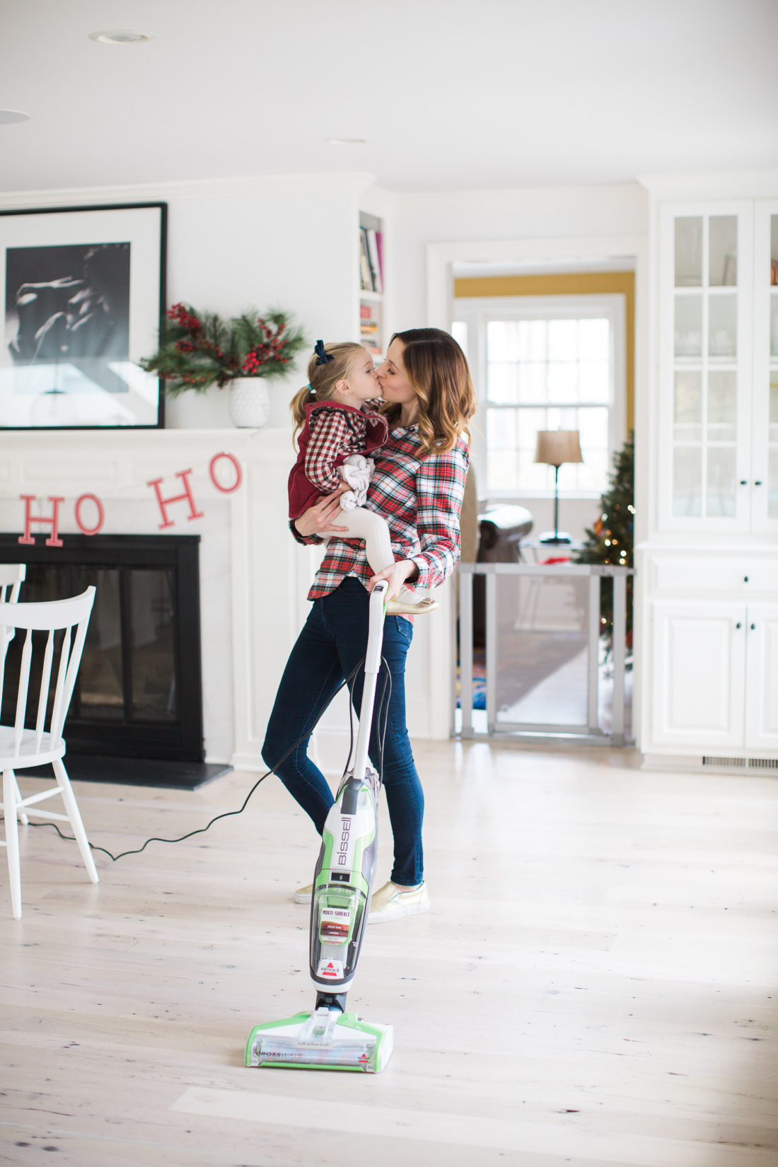 Eva Amurri Martino of lifestyle and motherhood blog REZTT holds her toddler daughter Marlowe in her arms while she vacuums her home and prepares for holiday parties