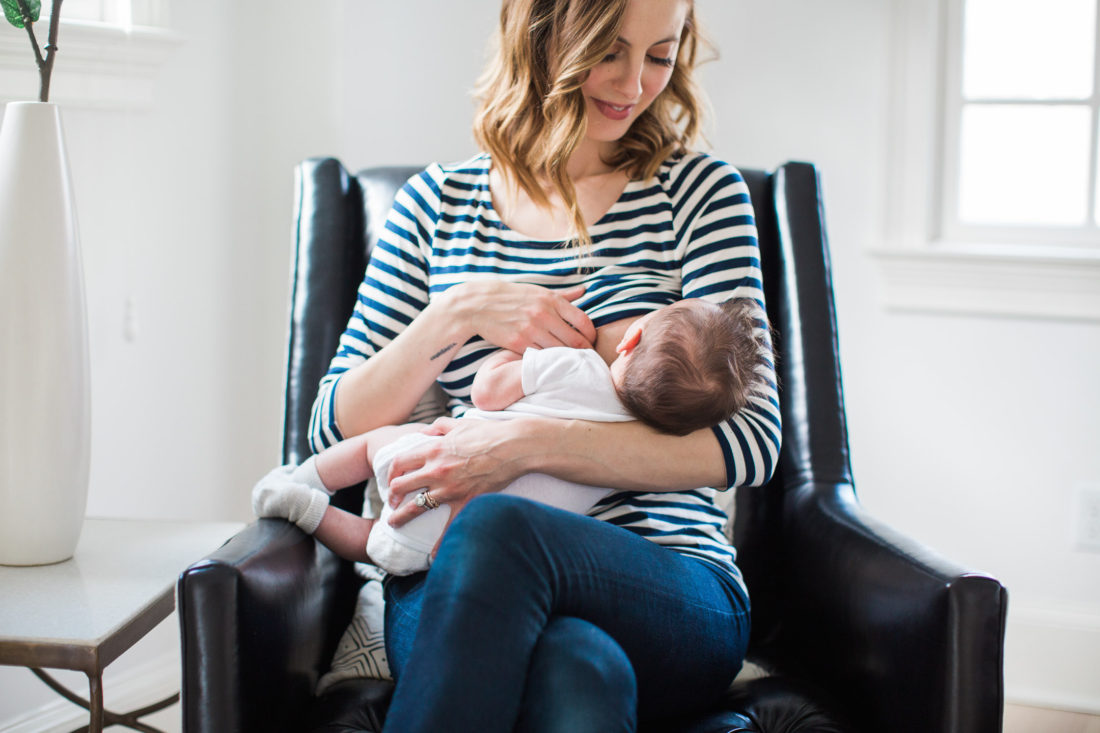 Eva Amurri Martino of lifestyle and motherhood blog REZTT breastfeeds her newborn son Major while wearing a striped breastfeeding shirt