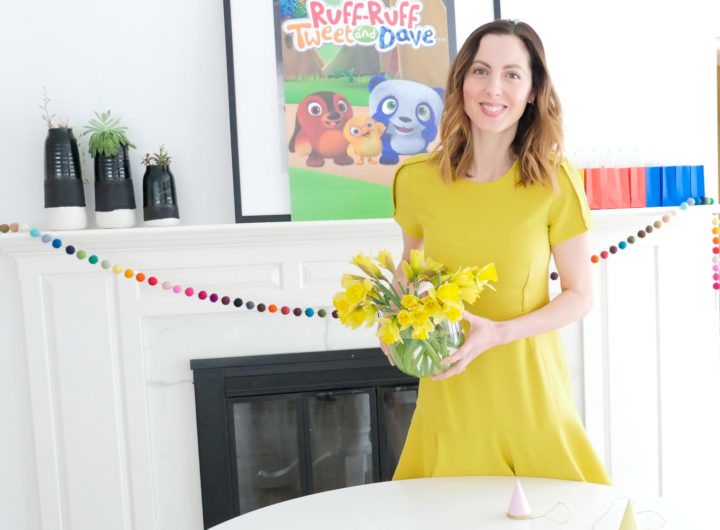 Eva Amurri Martino holds a vase of daffodils, wearing a yellow dress, for a post about entertaining for children