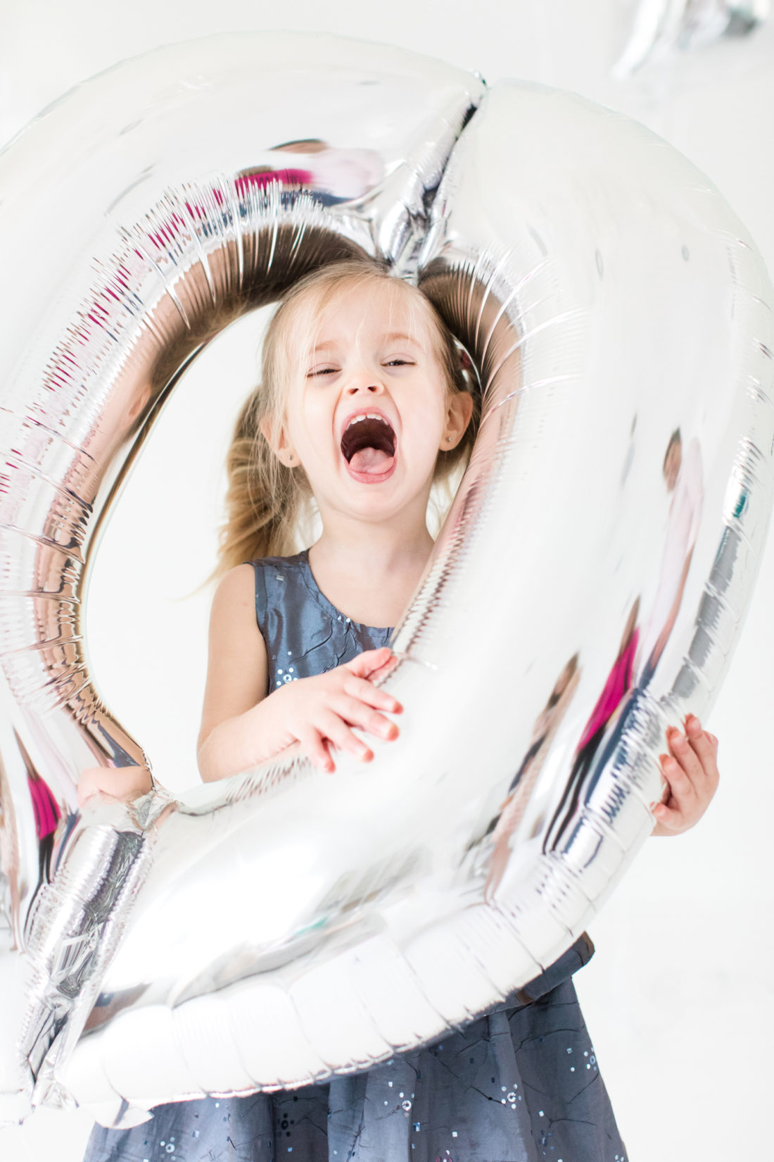 Marlowe Martino sticks her head through a silver balloon