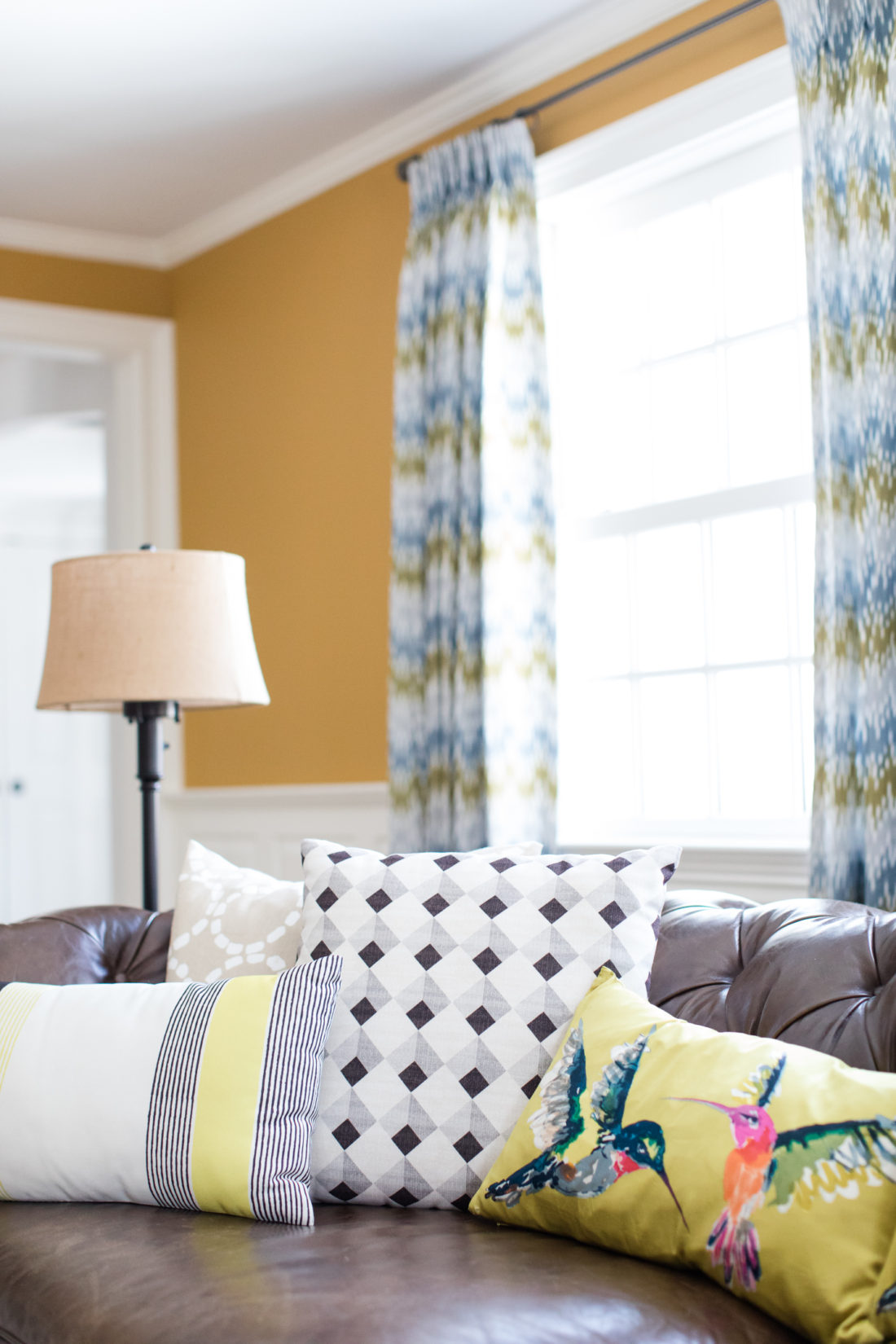 Black, white, natural, and yellow patterned couch pillows are scattered on the brown leather sofa in the formal living room of Eva Amurri Martino's connecticut home