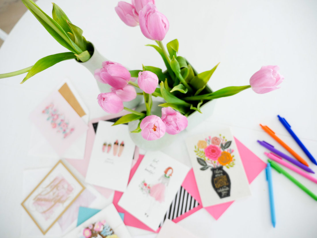 Colorful mother's day cards surround a bouquet of pink tulips