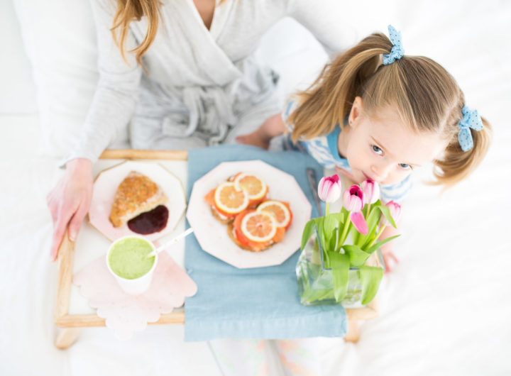 Marlowe Martino smells a bouquete of flowers on a mother's day breakfast tray