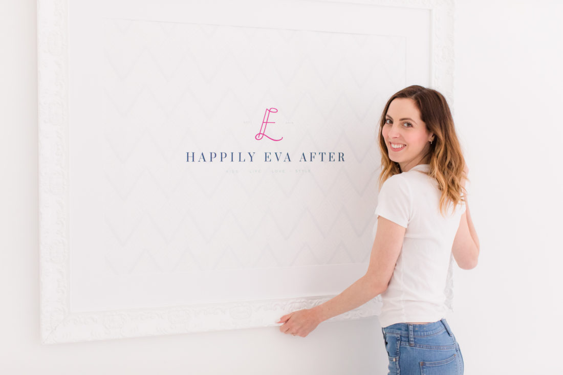 Eva Amurri Martino hangs up a framed poster of the REZTT logo on her studio wall
