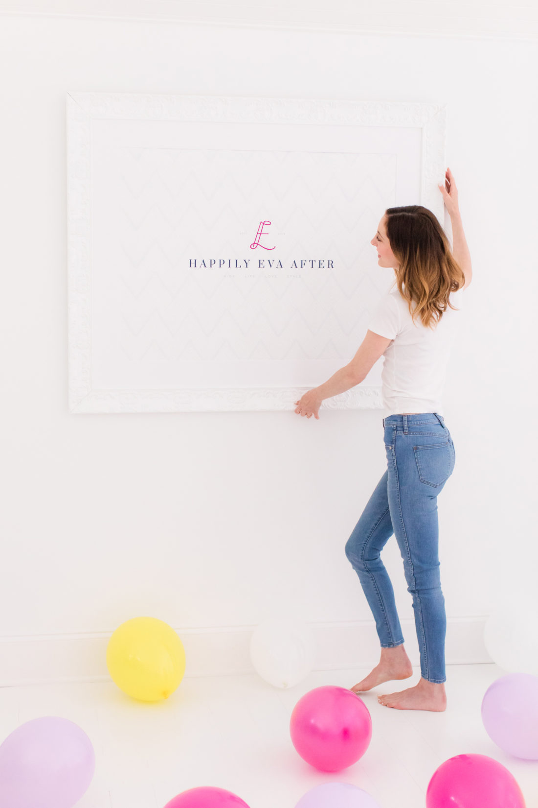 Eva Amurri Martino hangs up a framed poster of the REZTT logo on her studio wall