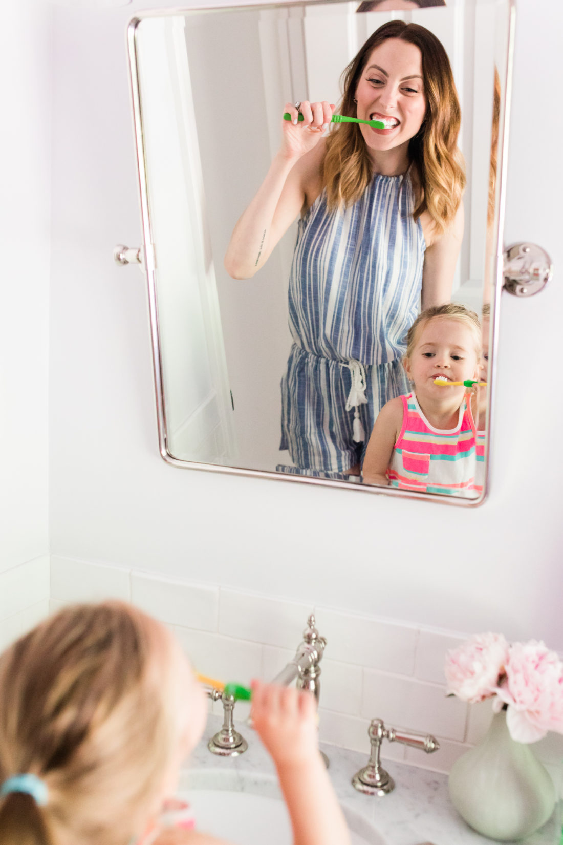 Eva Amurri Martino wears a blue and white striped romper and brushes her teeth with two year old daughter, Marlowe, in the bathroom of their Connecticut home