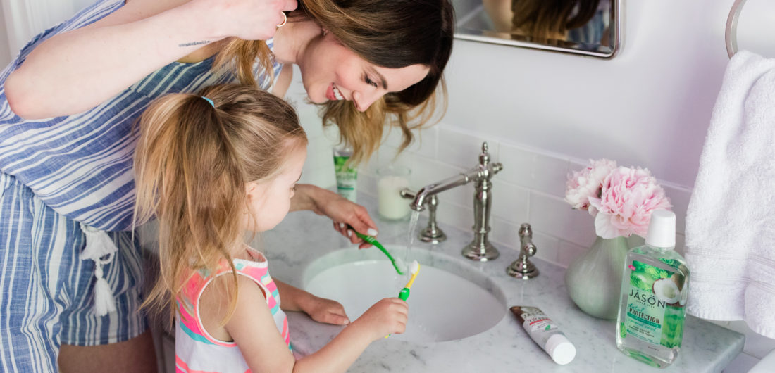 Eva Amurri Martino wears a blue and white striped romper and brushes her teeth with two year old daughter, Marlowe, in the bathroom of their Connecticut home