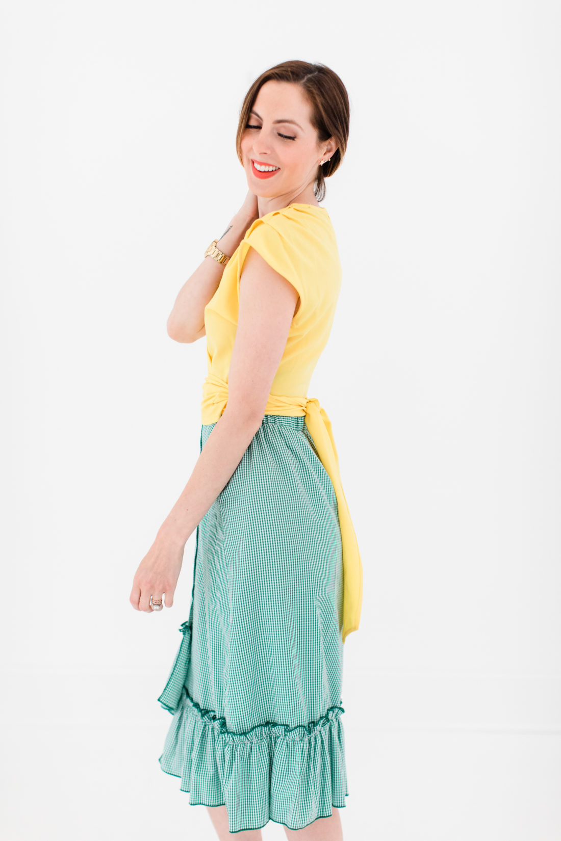 Eva Amurri Martino wears a bright yellow wrap top and gingham ruffle skirt as part of a post about packing for a trip