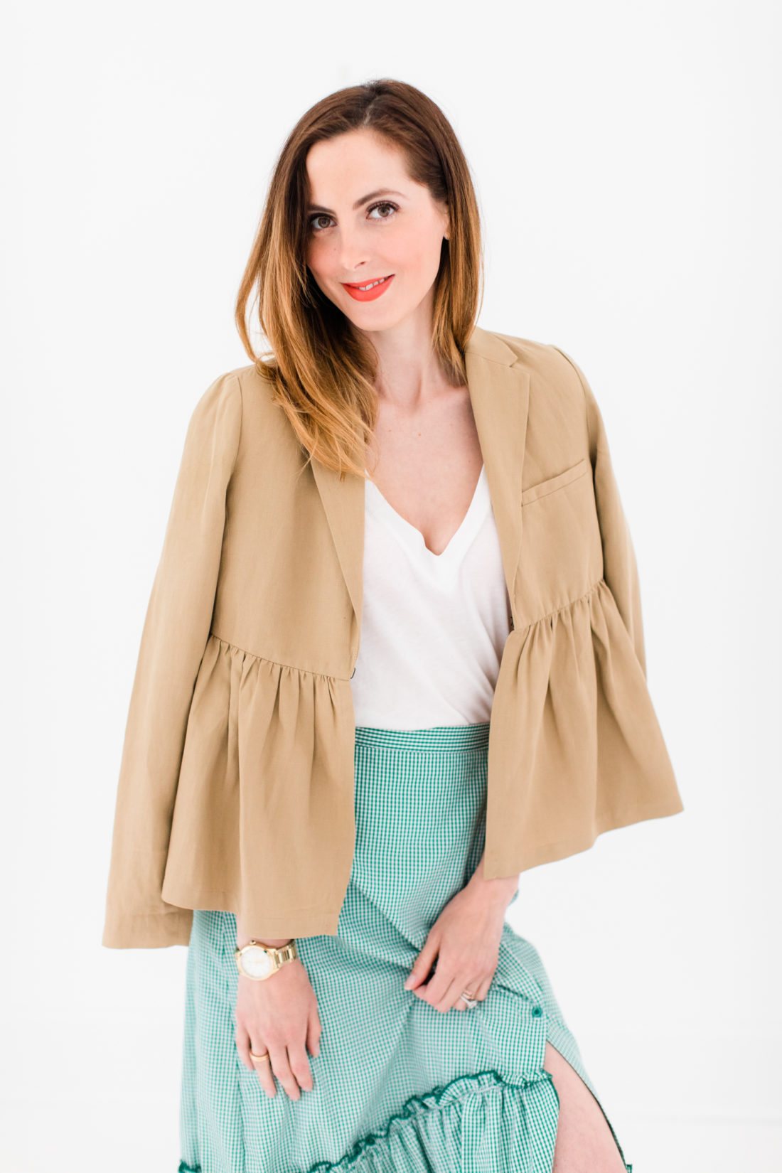 Eva Amurri Martino wears a green gingham ruffled skirt, white Tee, and tan ruffled jacket by BURU as part of a post about how to pack a suitcase