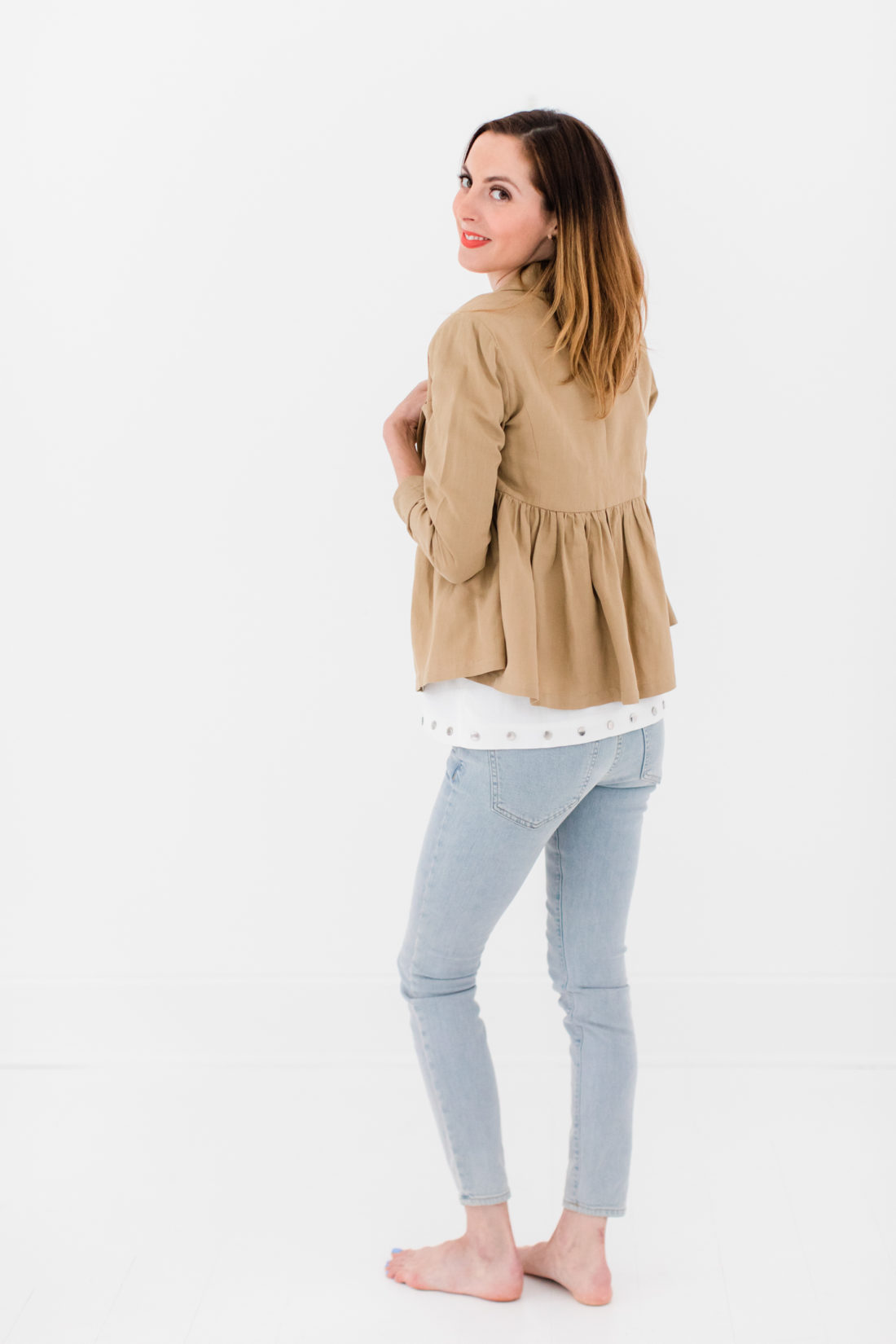 Eva Amurri Martino wears a white bow top, camel ruffle jacket, and jeans as part of a post about packing simply
