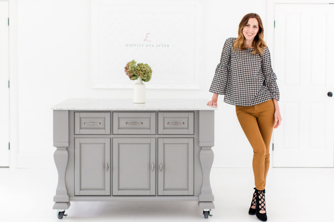 Eva Amurri Martino wears a pair of tan jeans, a black and white blouse, and poses in the REZTT studio