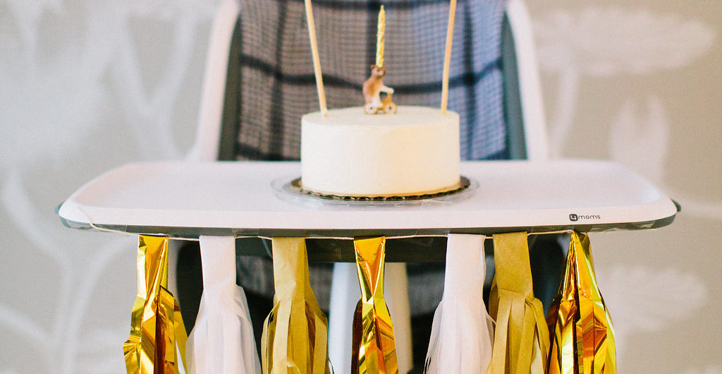 A white cake and porcelain bear on a bicycle candle holder with a home made flag bunting for Major Martino's first birthday party