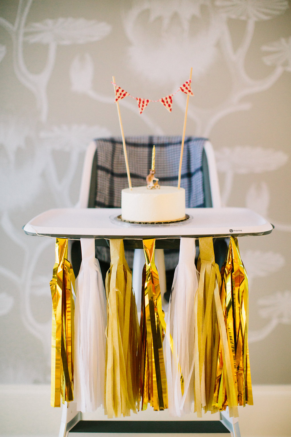 A white cake and porcelain bear on a bicycle candle holder with a home made flag bunting for Major Martino's first birthday party