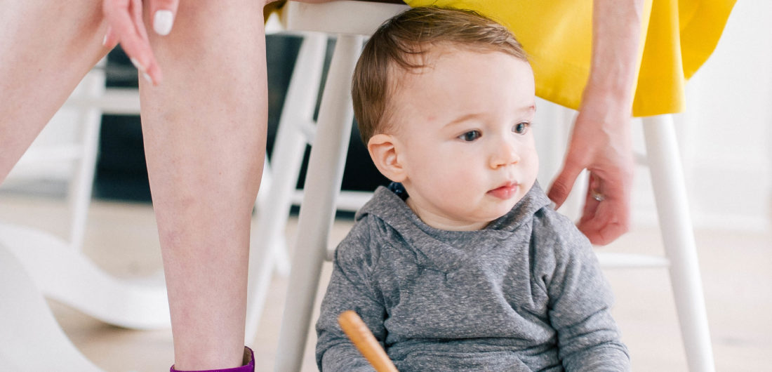Major Martino sits on the kitchen floor next to his Mom's chair and plays with a SpoonfulOne feeding bowl