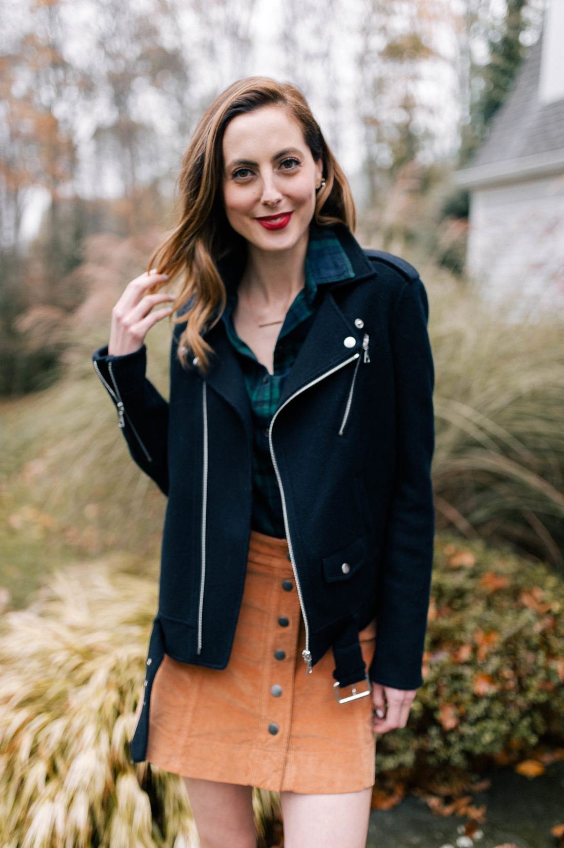 Eva Amurri Martino wears a plaid top, navy blue jacket, corduroy skirt, and black booties and walks down the pathway to her Connecticut home