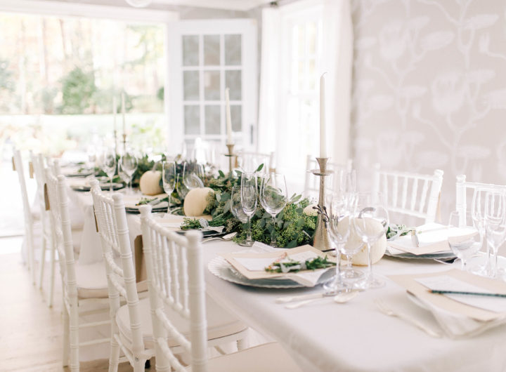 Crisp and modern white, flax, and silver tablescape at Eva Amurri Martino's Friendsgiving, featuring a long eucalyptus garland and white pumpkins