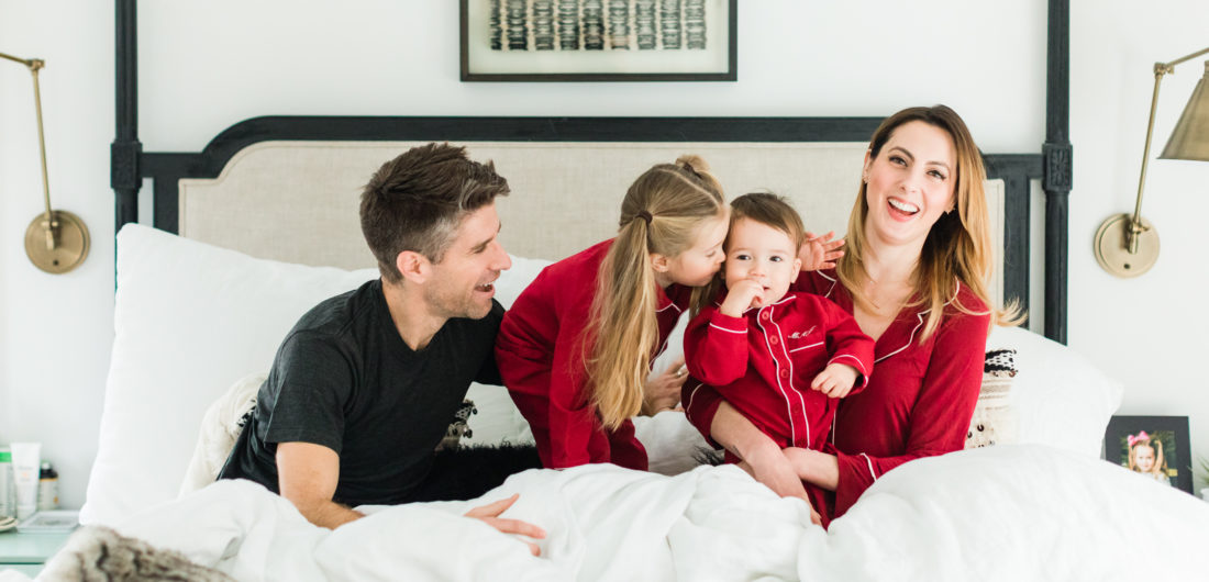 Eva Amurri martino, Kyle Martino, and children Marlowe and Major Martino cuddle in bed wearing red pajamas for Valentine's Day in the master bedroom of their Connecticut home