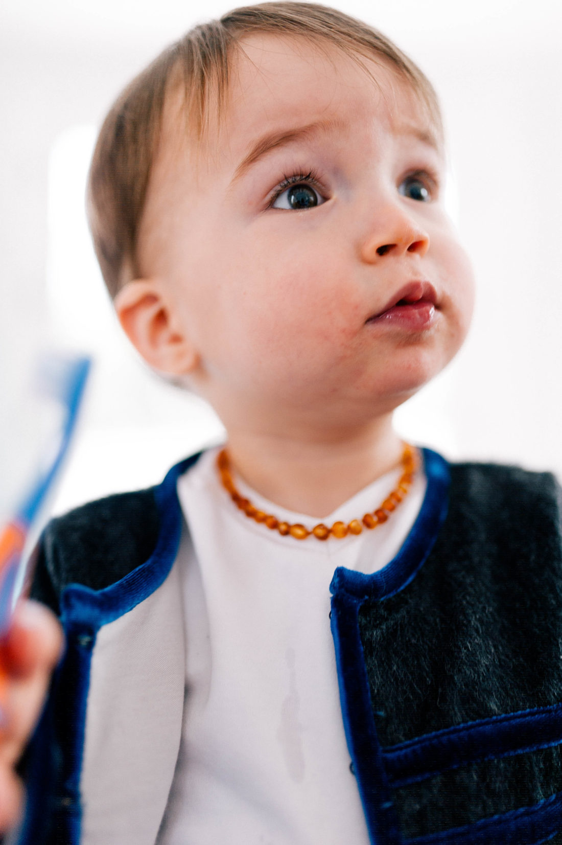 Major Martino wears a white tee shirt, a grey mohair jacket, and an amber teething necklace