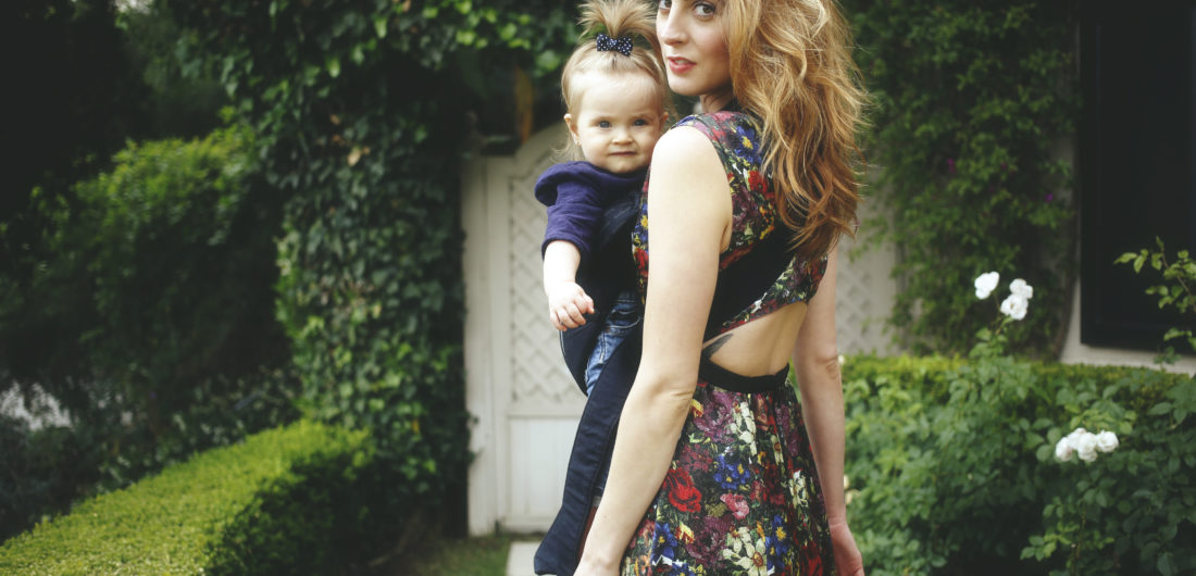 Eva Amurri Martino carrying her daughter Marlowe in a carrier with a suitcase ready to travel