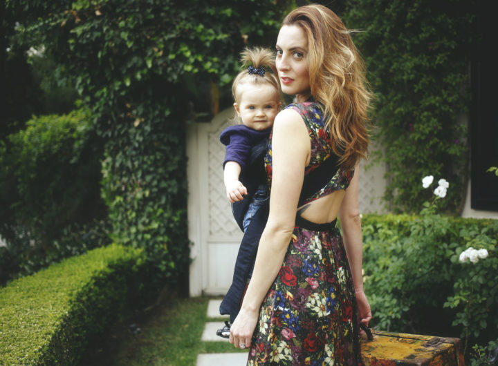 Eva Amurri Martino carrying her daughter Marlowe in a carrier with a suitcase ready to travel