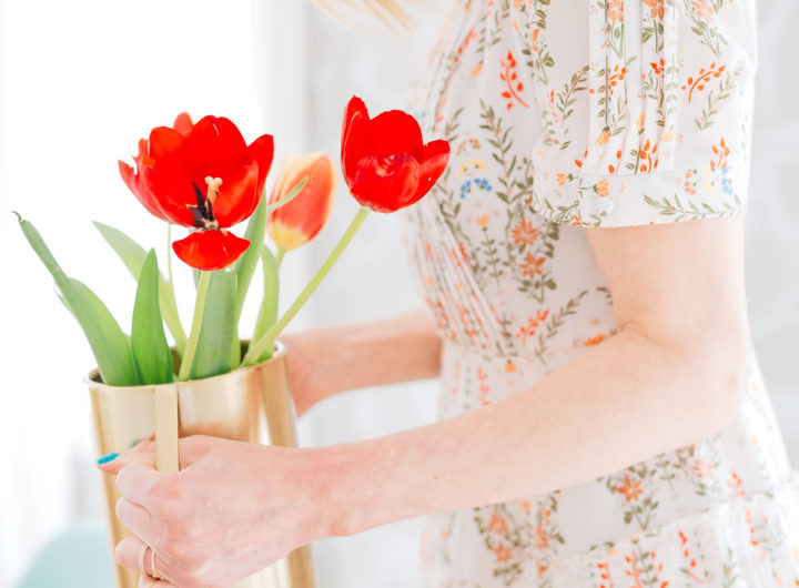Eva Amurri Martino wears a vintage-inspired dress holding a gold vase full of red tulips
