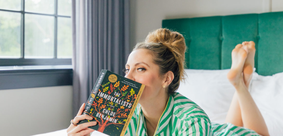Eva Amurri Martino lays in bed reading her newest book club pick: The Immortalists by Chloe Benjamin