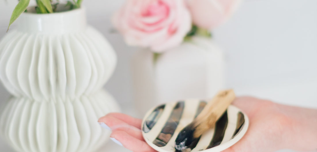 Eva Amurri Martino holding a smudge bowl with sage, and a piece of palo santo wood to cleanse the energy in her Westport CT home