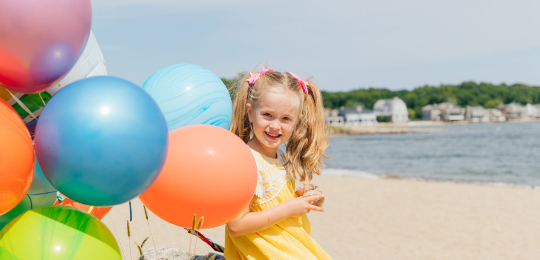 Marlowe Martino holds balloons on the beach in Connecticut to commemorate her 5th birthday