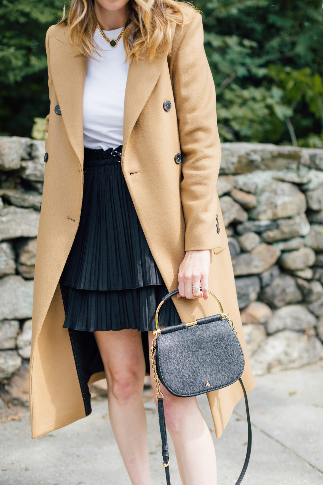 Eva Amurri Martino wears a camel coat, a black skirt and a white top as a neutral color palette