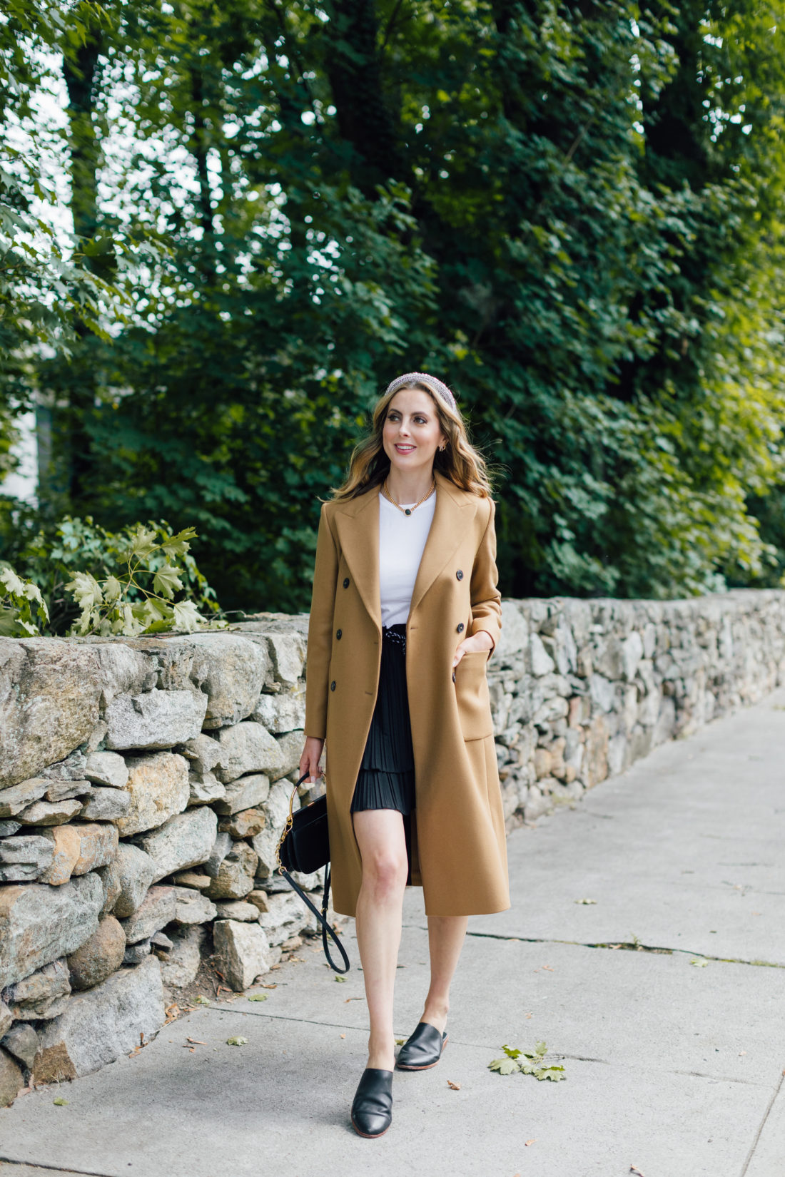 Eva Amurri Martino wears a camel coat, a black skirt and a white top as a neutral color palette