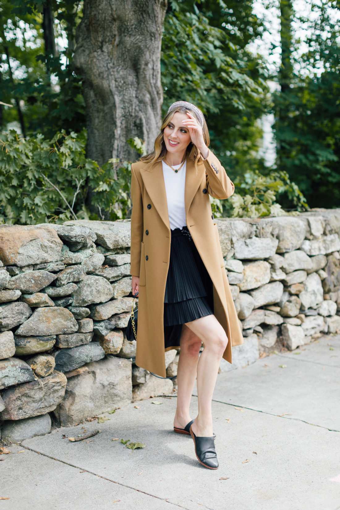 Eva Amurri Martino wears a camel coat, a black skirt and a white top as a neutral color palette