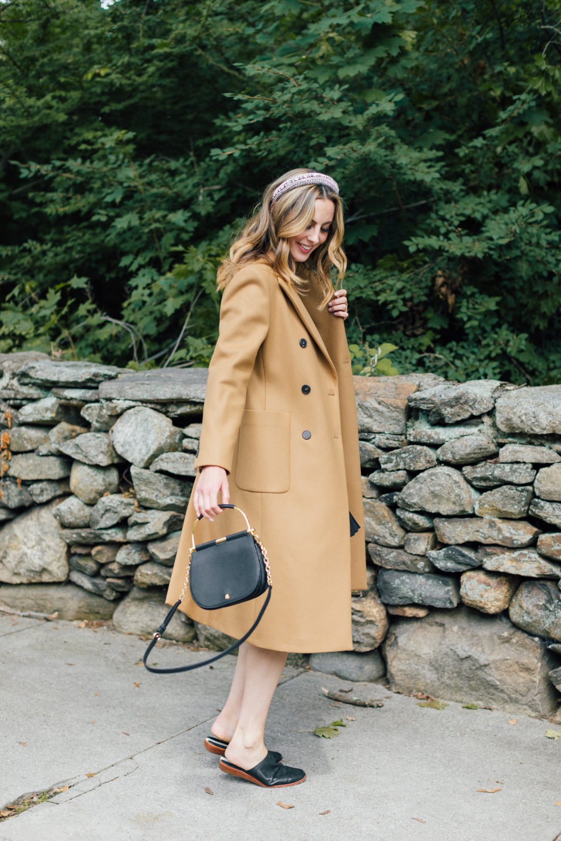 Eva Amurri Martino wears a camel coat, a black skirt and a white top as a neutral color palette