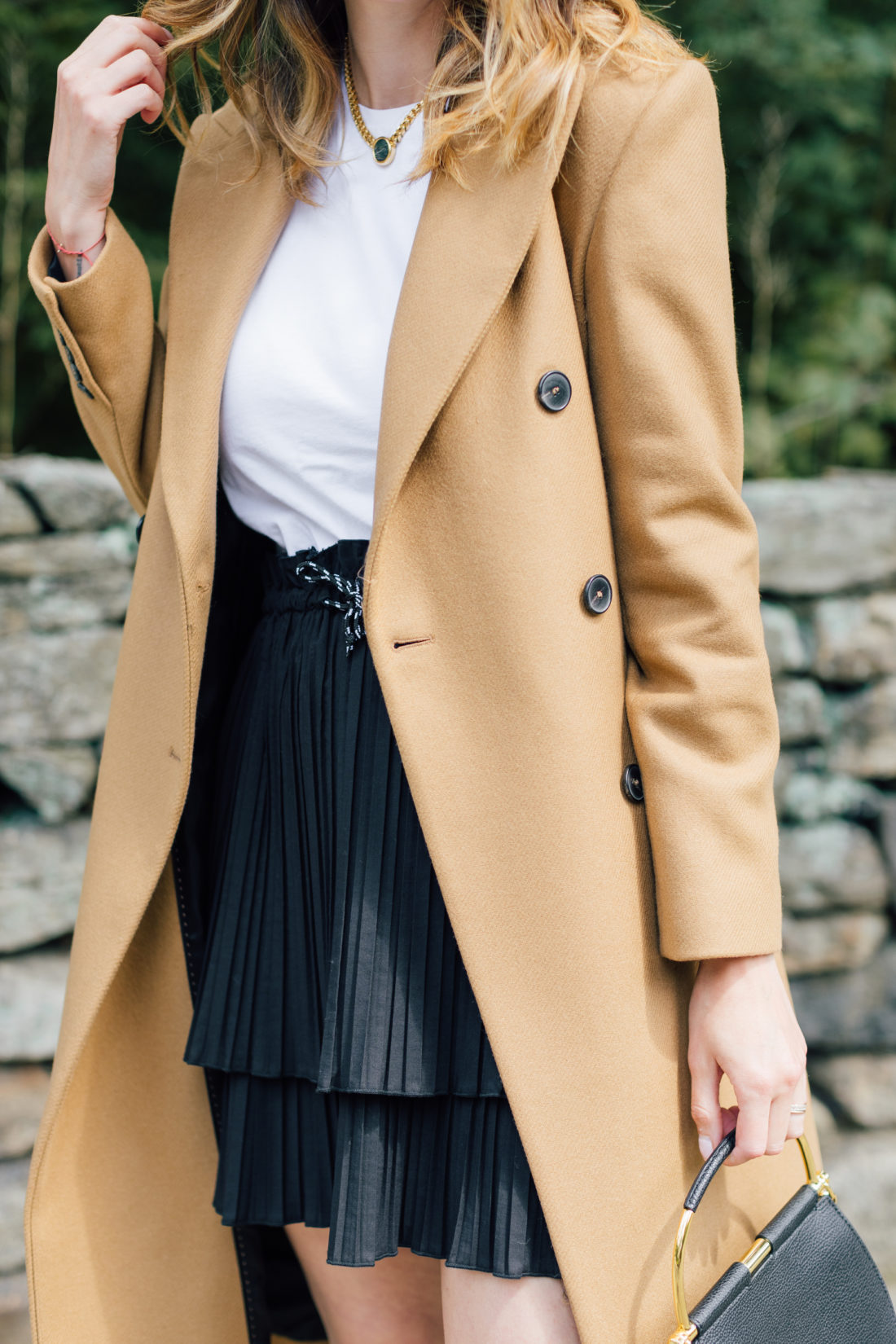 Eva Amurri Martino wears a camel coat, a black skirt and a white top as a neutral color palette